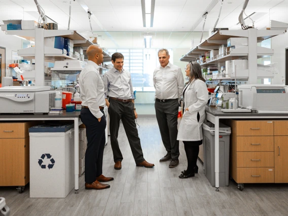 The four members of the Aspiro team standing in a lab talking with one another. 
