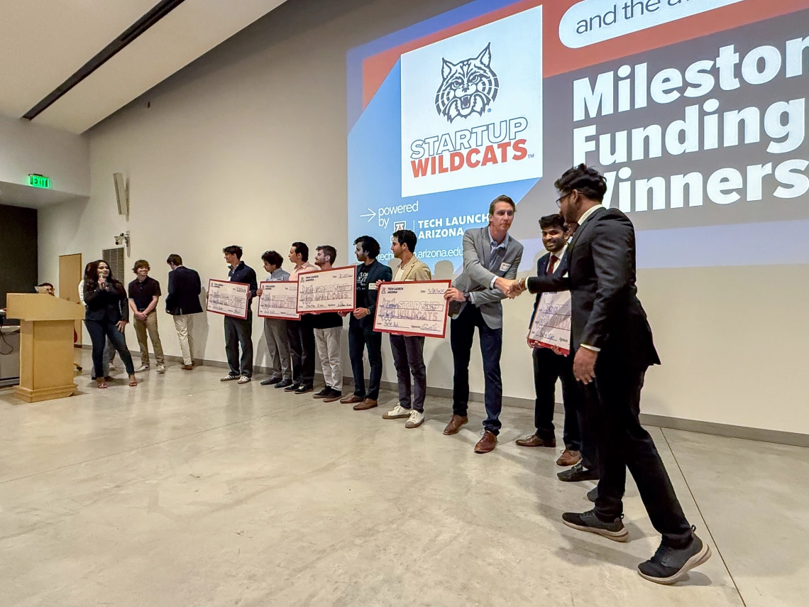 Startup Night Milestone Funding winners receiving their checks.