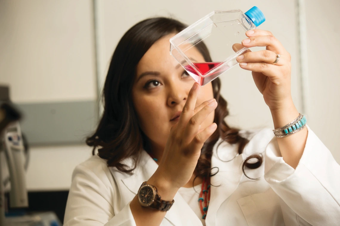 Student observing a fluid in a clear bottle at the College of Medicine Phoenix. Student observing a fluid in a clear bottle at the College of Medicine Phoenix.